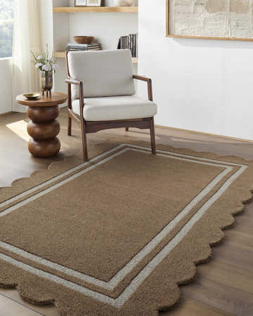 Living room scene with a Chogan Umber Area Rug. The rug is wool, brown with scalloped edges, and sits under a chair and side table. Roomscene-Rectangle