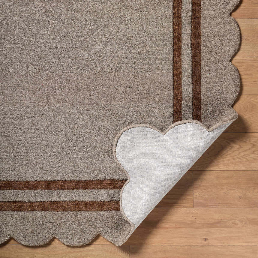 Close-up of the hand-tufted Chogan Charcoal Area Rug showing wool texture, striped pattern, and scalloped edge. Fold