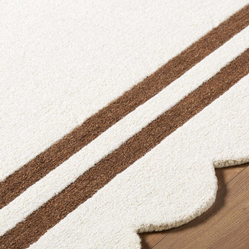 Close-up of the hand-tufted Chogan Ivory Area Rug. Features a striped brown pattern and a scalloped edge. 100% Wool. Texture