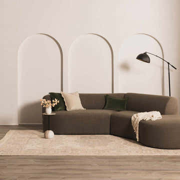 Living room scene with a Chaela Ivory & Lavender Area Rug, brown sectional, neutral walls, and modern floor lamp. Roomscene-Rectangle