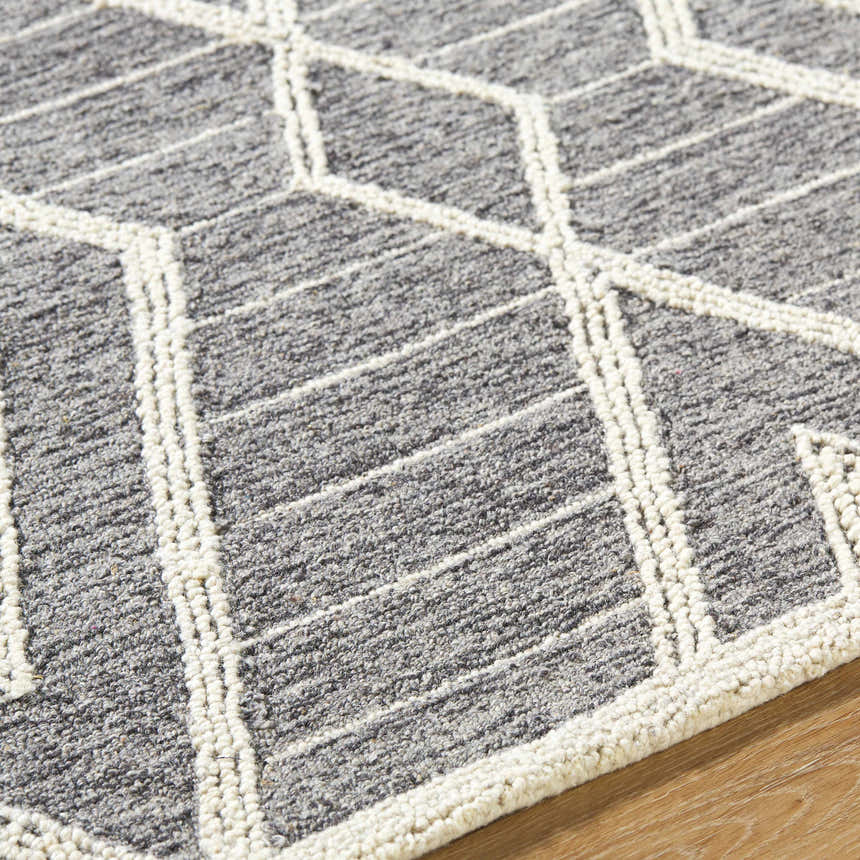 Close-up of the Ceanna Area Rug. Gray wool rug with off-white geometric diamond pattern, hand-tufted texture. Texture