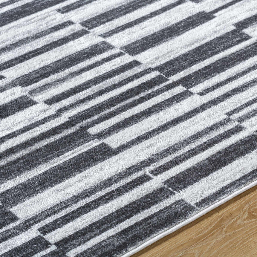 Close-up of the Cemach Cream Area Rug. Features a contemporary charcoal and silver gray geometric pattern. Texture