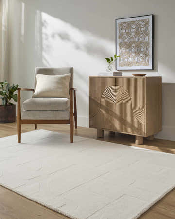 Living room scene with ivory Chizue Area Rug, gray chair, and wood cabinet with geometric art. Roomscene-Rectangle