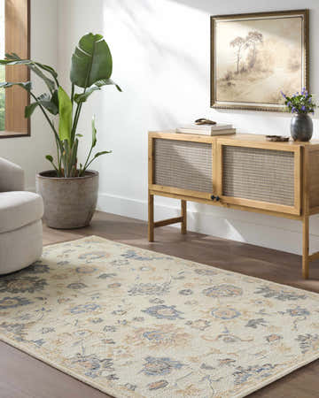 Living room scene with a cream Candid Oushak Area Rug, wood cabinet, potted plant, and neutral armchair. Roomscene-Rectangle