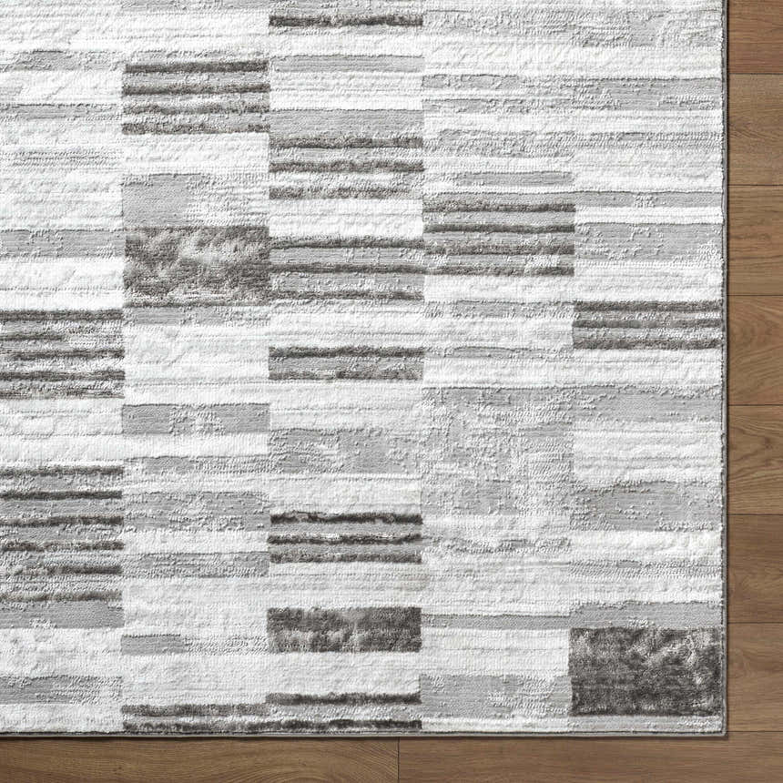 Close-up of the contemporary Chiaki Light Gray Area Rug with ivory, silver, and medium gray geometric pattern. Corner
