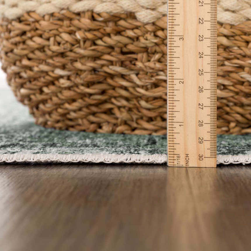 Close-up of Green Holi-4605 rug edge with ruler and basket, showing texture and rug thickness. Pile