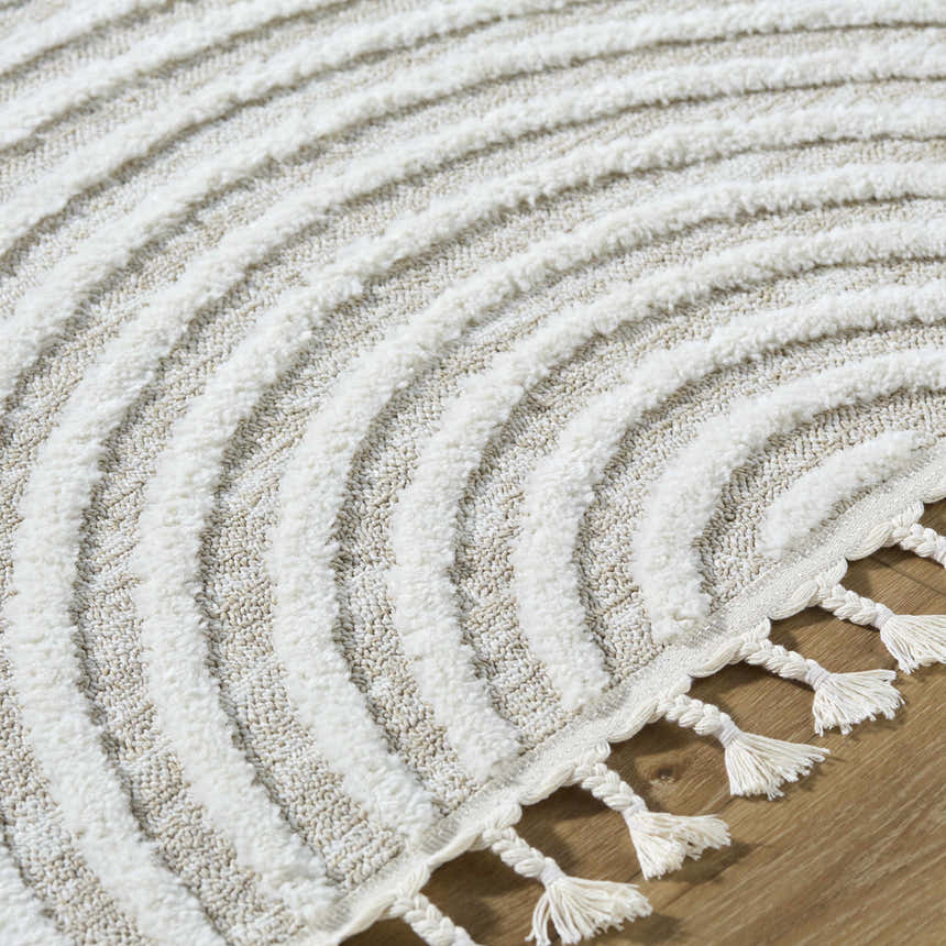 Close up of the Cassie Area Rug featuring cream and peach hues, textured lines, and tassel details. Texture