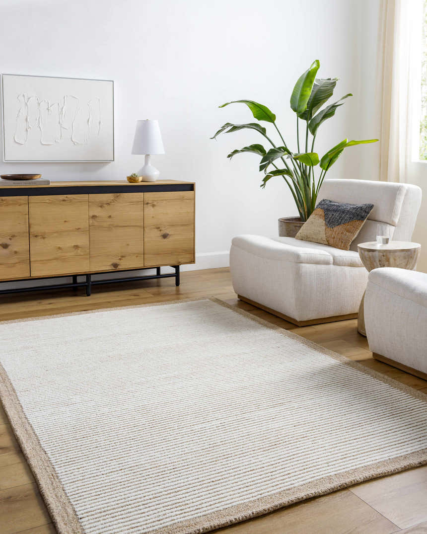 Living room scene with a beige and ivory Cianna Area Rug, wood cabinet, and white armchairs. Roomscene-Rectangle