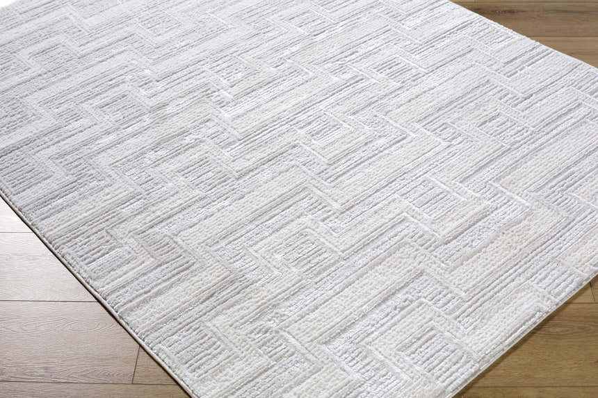Close-up of the cream and ivory Cormac Area Rug showing its geometric pattern and soft texture. Corner