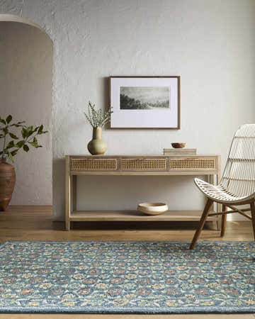 Living room scene with blue floral Ardith Area Rug, wood console table, white chair, and neutral decor. Roomscene-Rectangle