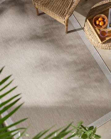 Outdoor patio scene featuring the Chetan Tan outdoor rug, wicker chair, and side table with drinks. Roomscene-Rectangle