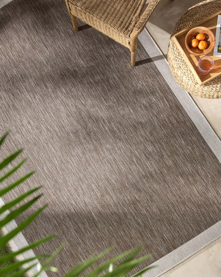 Patio scene with Chetan Dark Brown Area Rug, wicker furniture, and neutral tones. Roomscene-Rectangle