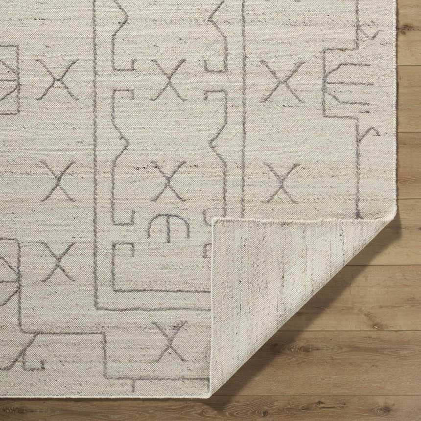 Close up of the hand woven Chanda Area Rug. Beige wool with gray geometric pattern and folded corner. Fold
