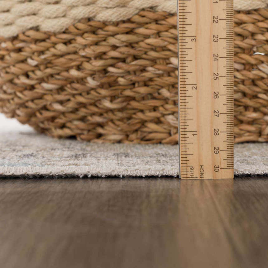 Close-up of Beige Holi-4600 Washable Area Rug edge with ruler, showing pile height next to a woven basket. Pile