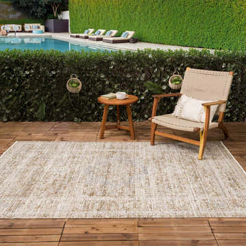 Outdoor poolside patio with beige Aistys Washable Area Rug, wood chair, and small table. Relaxing, neutral tones. Roomscene-Rectangle