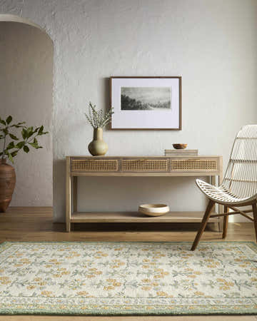 Entryway with Alonsa Sage Area Rug, light wood console table, white textured walls, and woven chair. Farmhouse style. Roomscene-Rectangle