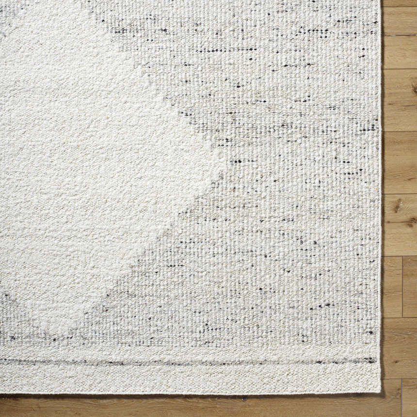Close-up of Ethara Ivory Charcoal rug showing wool texture and global pattern on wood floor. Clearance. Corner