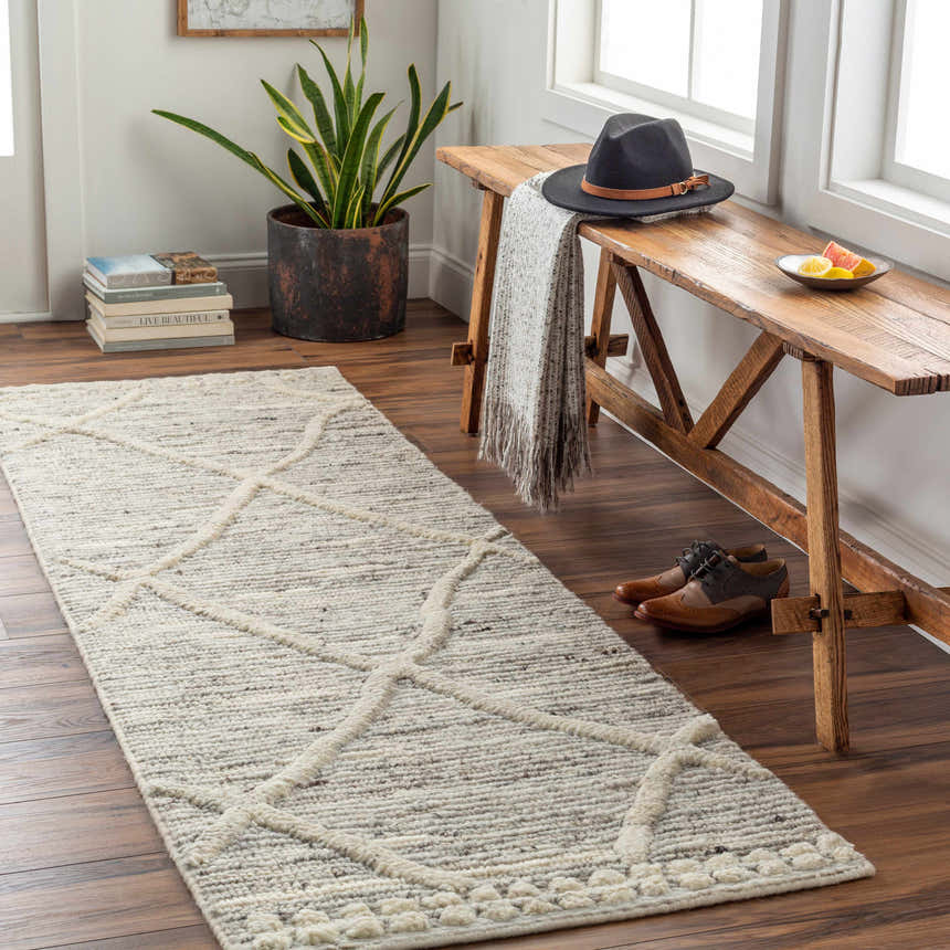 Entryway scene with a cream Donsol Area Carpet, wood bench, hat, and shoes on a dark wood floor. Roomscene-Runner