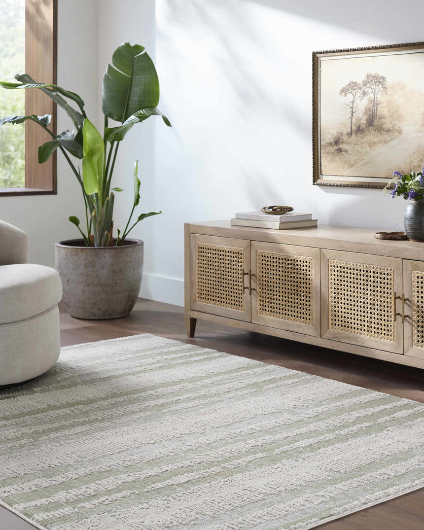 Living room scene with an Asmara Green Area Rug, light wood cabinet, and neutral swivel chair. Roomscene-Rectangle