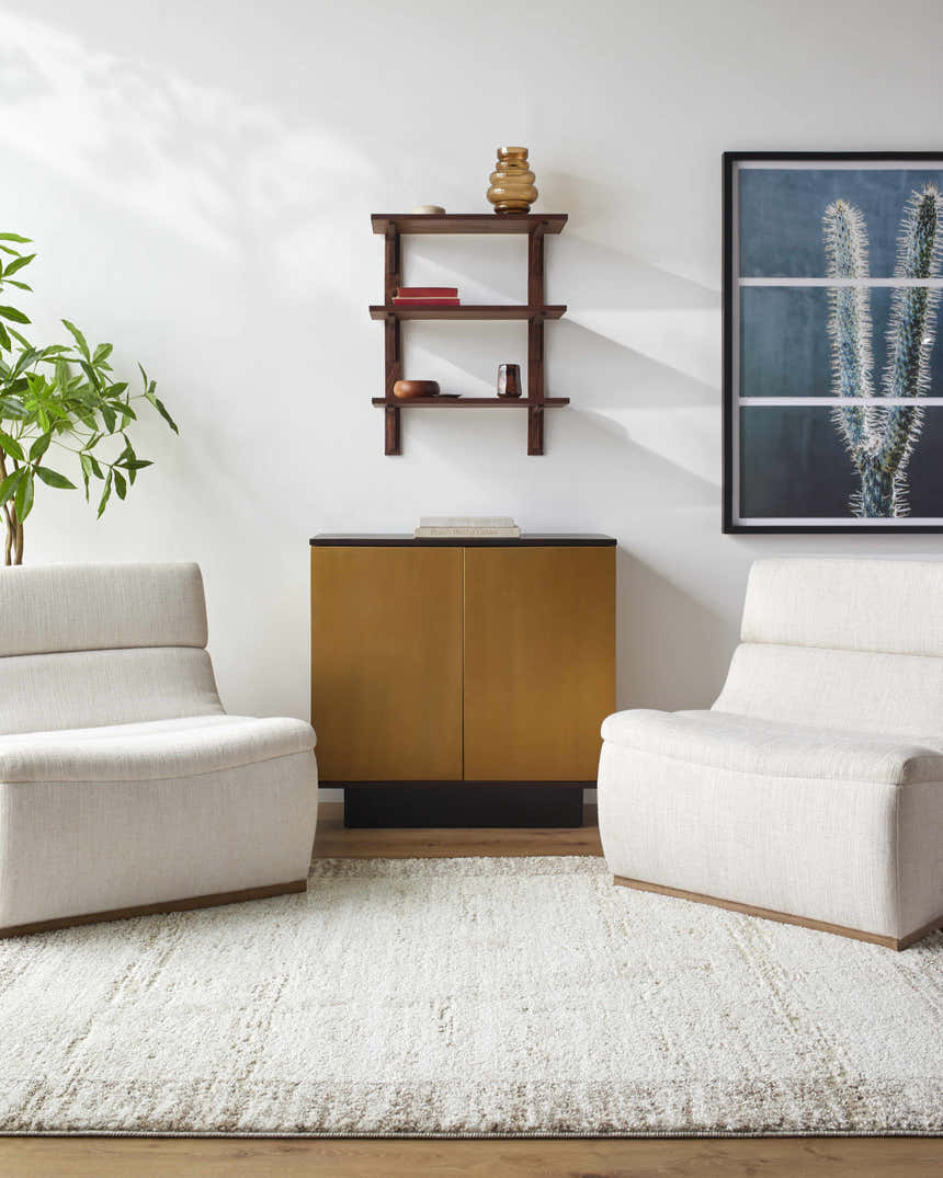 Living room scene with ivory chairs on a light Dhaval Ivory Area Rug, gold cabinet, and modern decor. Roomscene-Rectangle