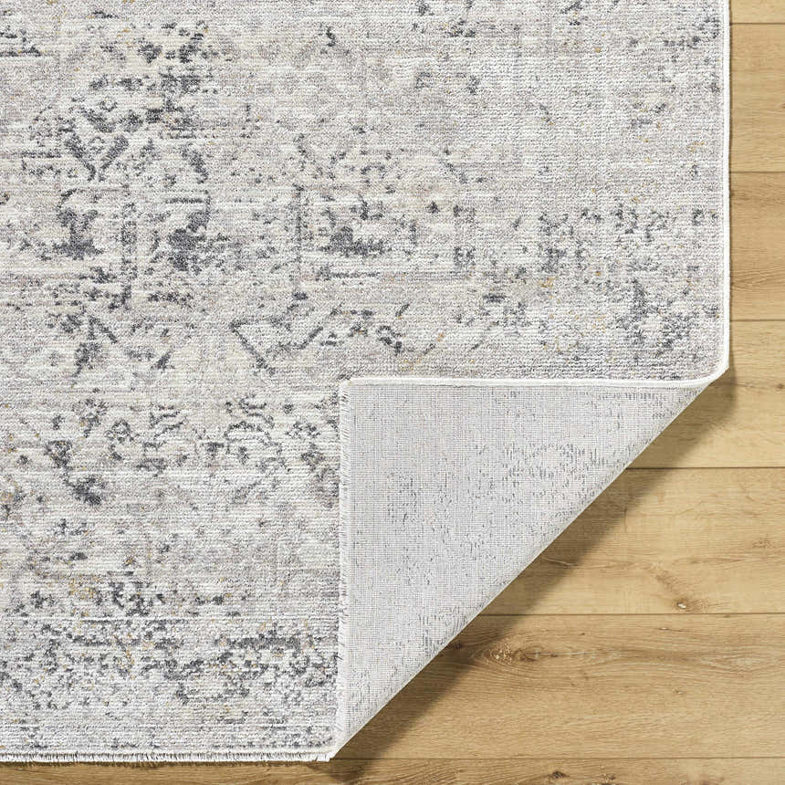 Close-up of the Alivia Area Rug showing charcoal, gray, and ivory tones. Traditional farmhouse style rug with folded corner. Fold