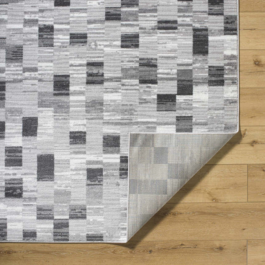 Close-up of the Alagan Medium Gray Area Rug with a geometric block pattern in light silver, sage, and silver gray hues. Fold