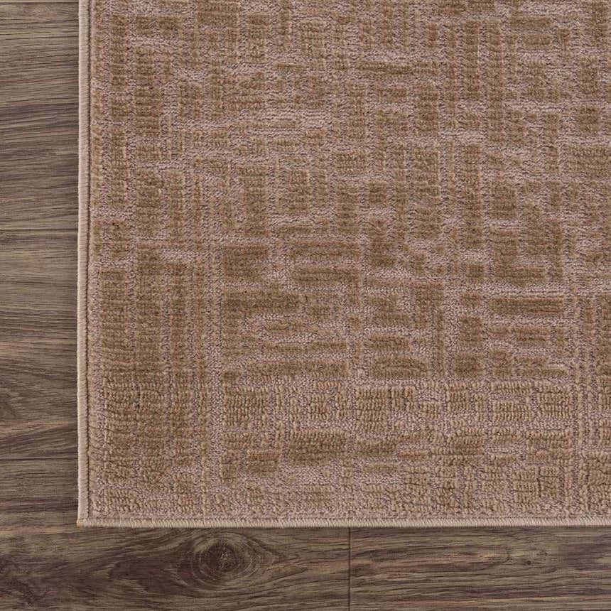 Close-up of the Leanna Light Brown Washable Area Rug. The rug has a subtle geometric pattern and a textured surface. Corner