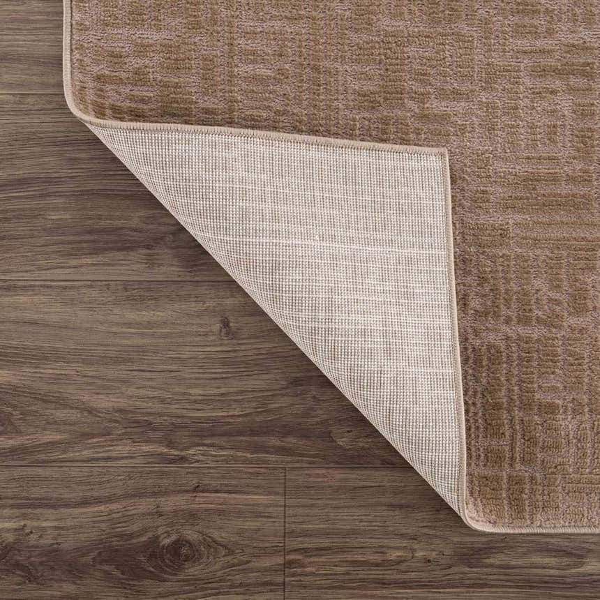 Close-up of the Leanna Light Brown Washable Area Rug showing its texture, backing, and light brown color on a wood floor. Fold