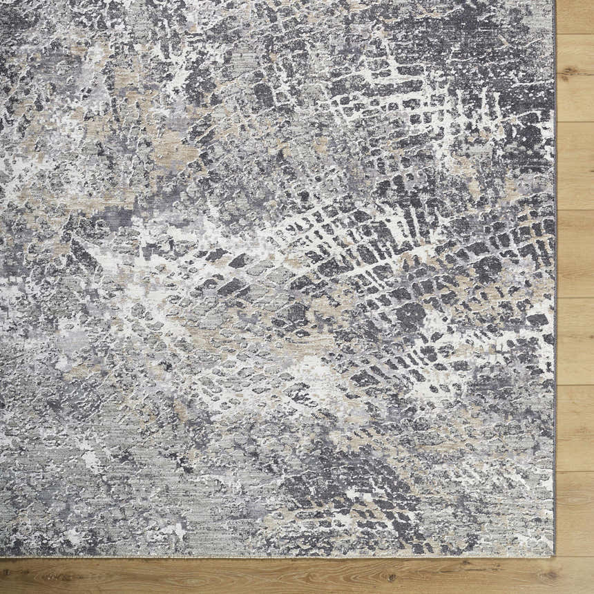 Close-up of the Aolani Medium Gray Area Rug showing its abstract black, gray, ivory, and tan pattern and textured weave. Corner