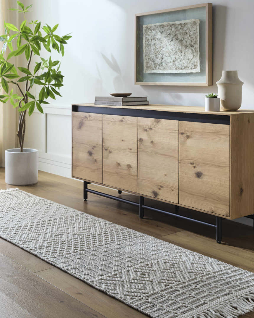 Living room scene with a light wood cabinet and the Egil Wool-blend Area Rug in off-white with a geometric pattern. Roomscene-Runner