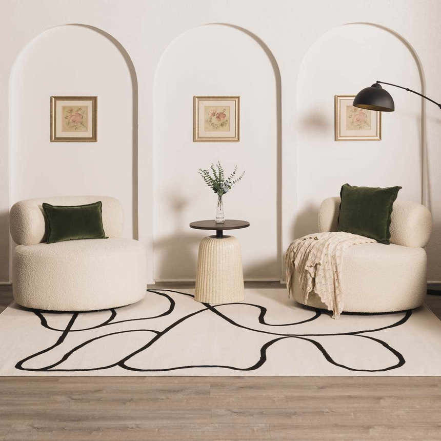 Living room scene with Eilir Modern Low Profile Boho Rug, cream chairs, and black accents for a contemporary, minimalist look. Roomscene-Rectangle