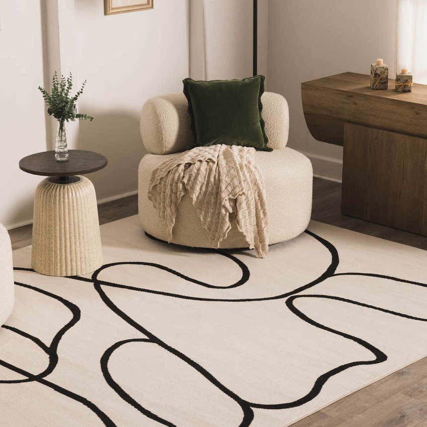 Living room scene with bone Eilir Modern Boho Rug, round chair, and side table. Black abstract lines on the rug add a modern touch. Roomscene-Rectangle