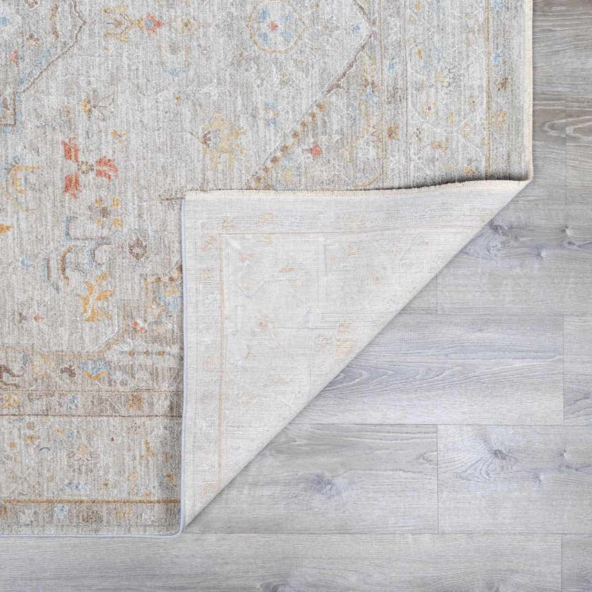 Close-up of the Engin Thick Luxe Area Rug showing its traditional amber, pink, and gray pattern and woven texture. Fold