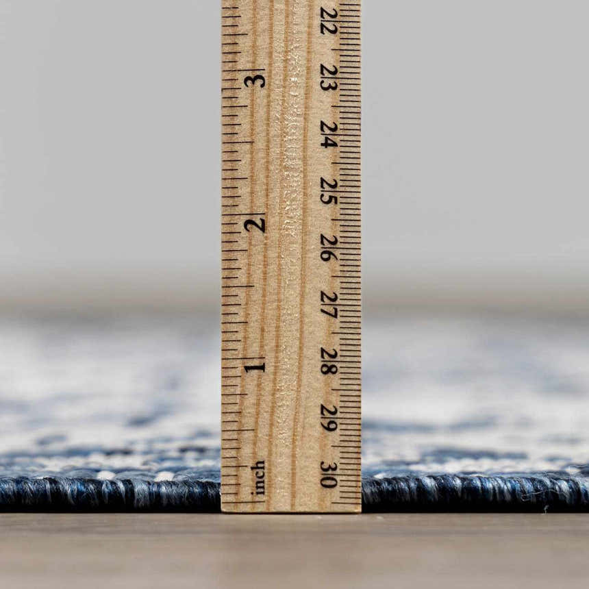Close-up of the Etoile Navy Blue Performance Rug showing rug thickness with a ruler. Pile