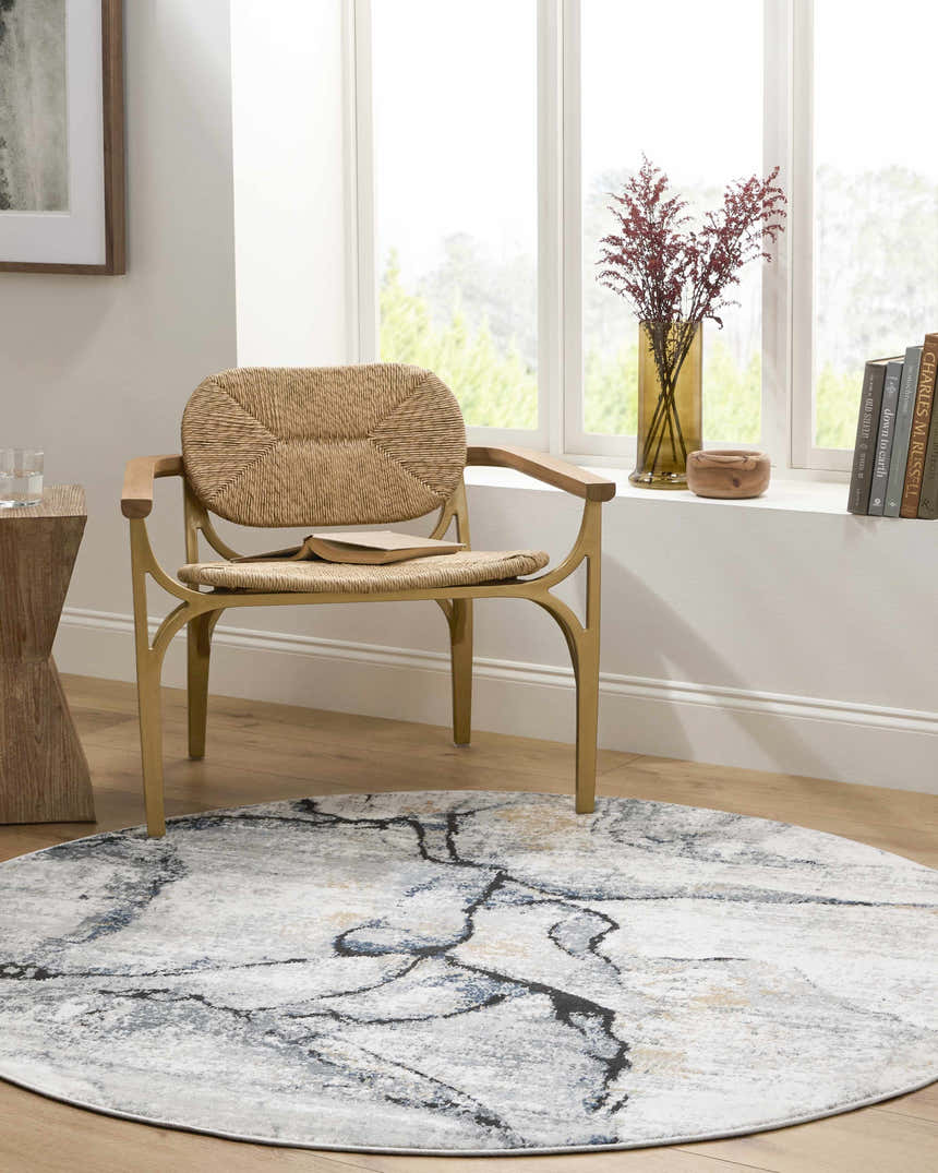 Bright reading nook with a round Fremantle Gray Marble Rug, woven chair, and natural wood accents. Roomscene-Round