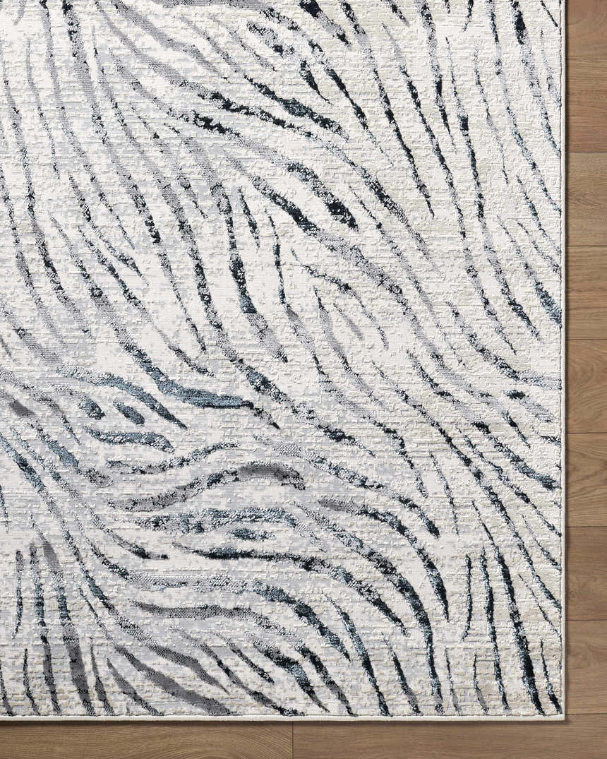 Close up of the Arlene Area Rug. Contemporary style rug in black, cream, gray, and light slate with a textured pattern. Corner
