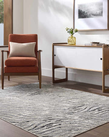 Living room scene with an Arlene Area Rug in black, cream, and gray. Contemporary style with an orange chair and modern cabinet. Roomscene-Rectangle