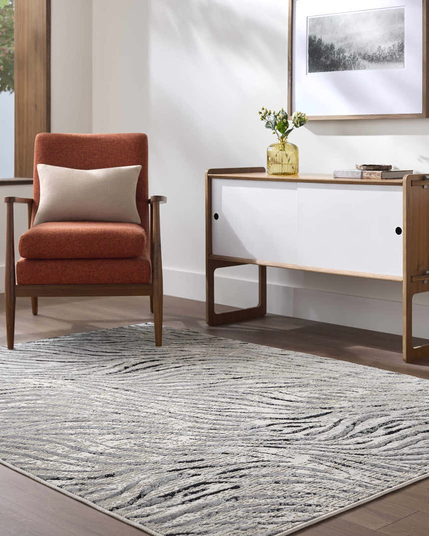 Living room scene with an Arlene Area Rug in black, cream, and gray. Contemporary style with an orange chair and modern cabinet. Roomscene-Rectangle