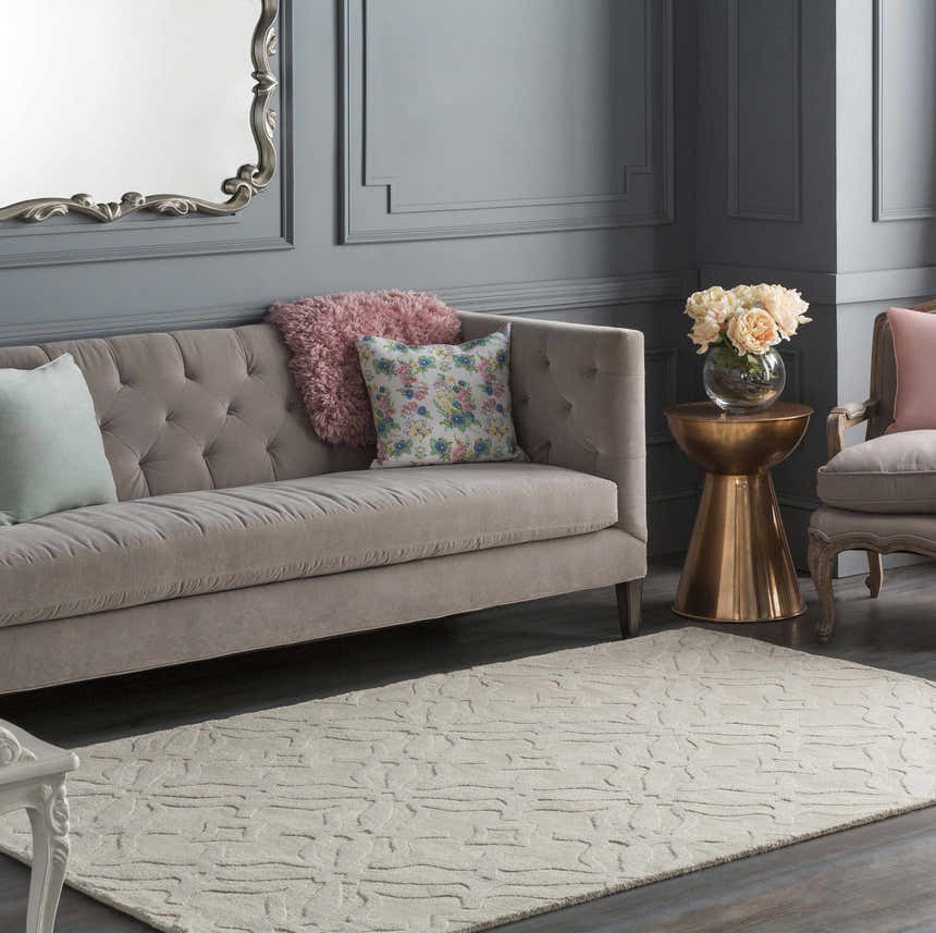 Living room with tufted sofa and Fyffe Embossed Beige Wool Area Rug. Neutral tones create a calming, contemporary space. Roomscene-Rectangle