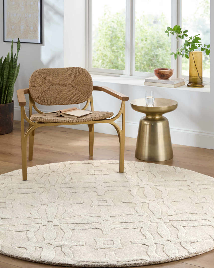 Sunlit room with a round Fyffe Embossed Beige Wool Area Rug, woven chair, and gold accent table. Roomscene-Round