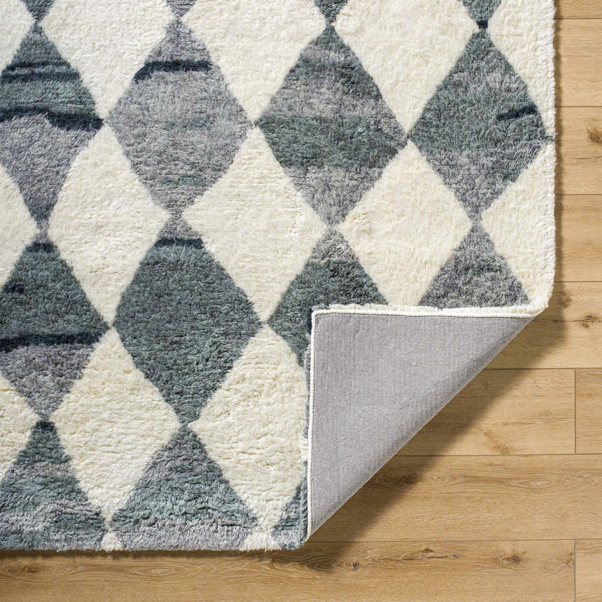 Close-up of the hand-tufted Azaria Baklava Wool Rug. Gray and light silver diamond pattern. Shows rug back. Farmhouse style. Fold