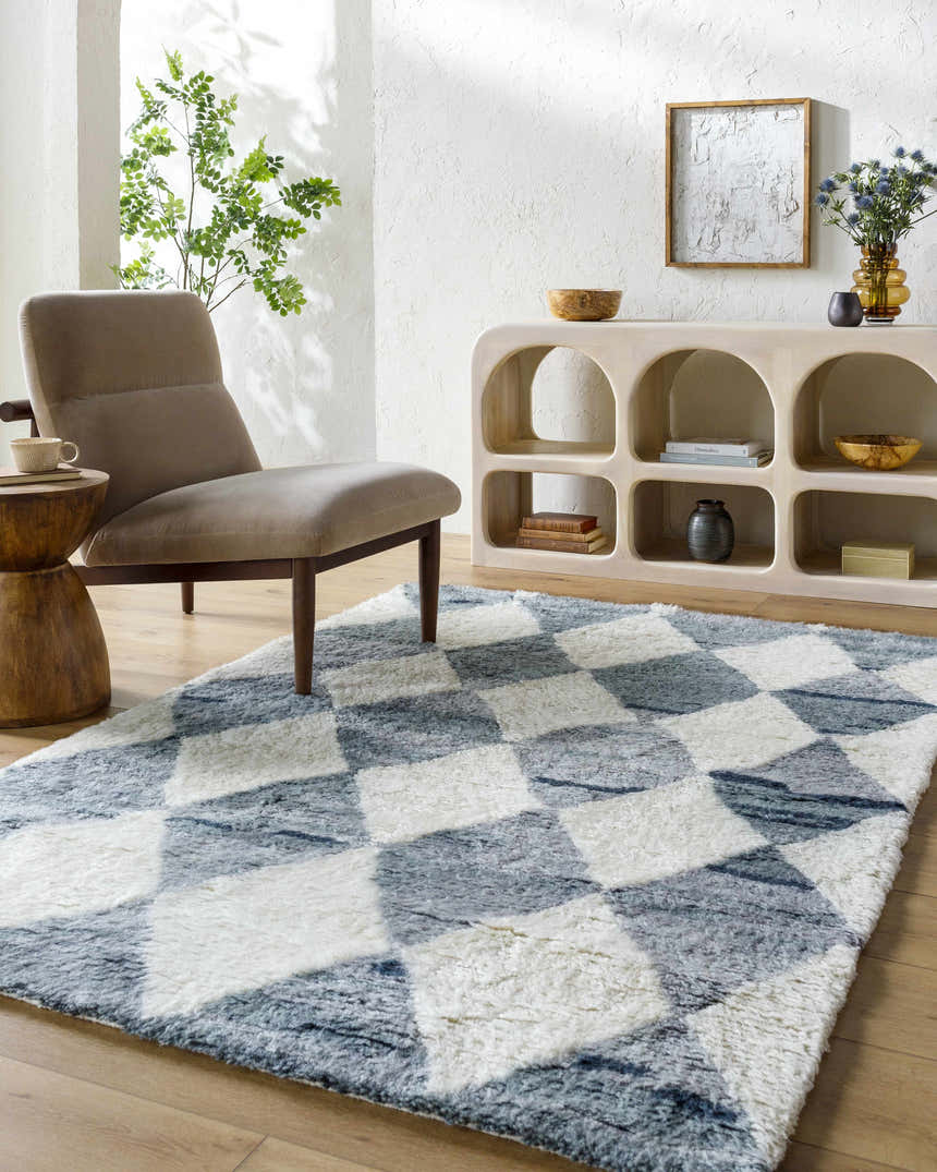 Living room scene with a gray armchair and the Azaria Baklava Wool Rug in gray and white with a diamond pattern. Roomscene-Rectangle