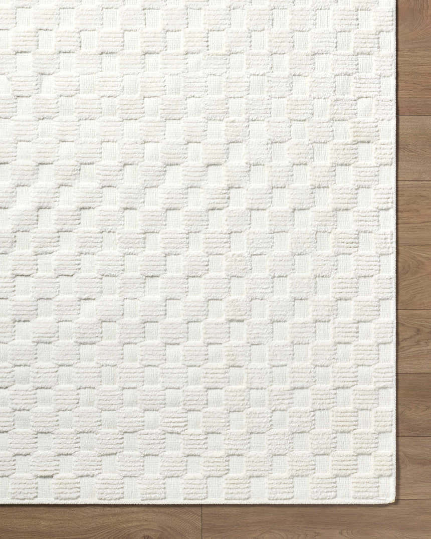 Close-up of the Anthea Off-White 3D Checkered Washable Rug. The rug has a raised, textured geometric pattern. Corner