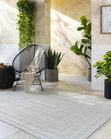 Sunlit patio scene with Avalos White Area Rug, black chair, and potted plants. Neutral tones create a calming, modern vibe. Roomscene-Rectangle