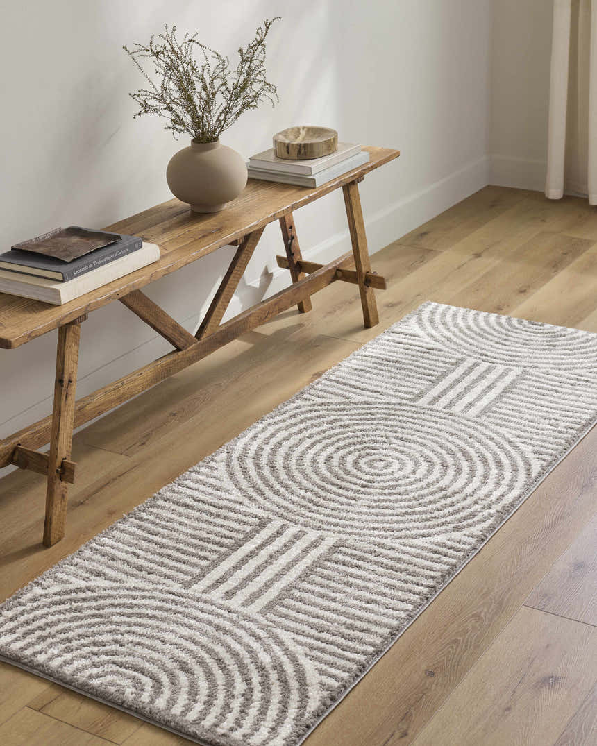 Hallway scene with Allard Charcoal Washable Area Rug runner, wood bench, vase, and books on light wood floors. Roomscene-Runner
