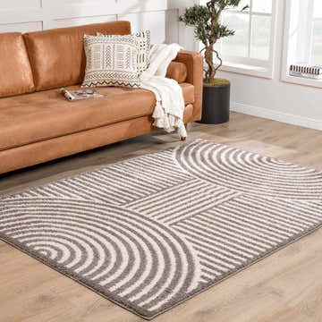 Living room scene with a Allard Charcoal Washable Area Rug, tan leather sofa, and wood floors. Modern, neutral tones. Roomscene-Rectangle