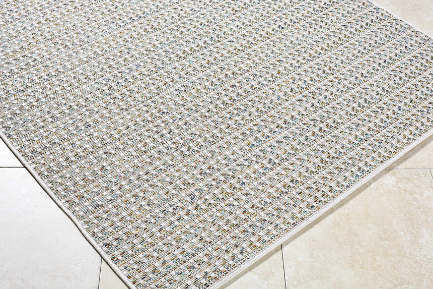 Close-up of the Ataret Ivory Area Rug, a machine-woven rug with charcoal, ivory, blue, gray, and tan tones. Corner