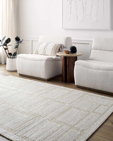 Living room scene with beige Alayka Area Rug, light neutral furniture, wood accents, and minimalist artwork. Roomscene-Rectangle