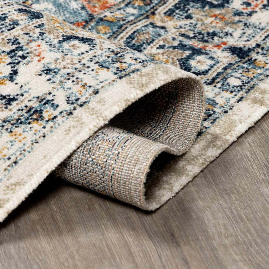 Close-up of rolled Dorval Traditional Rug showing cream, denim, and rust colors in an oriental pattern. Fold
