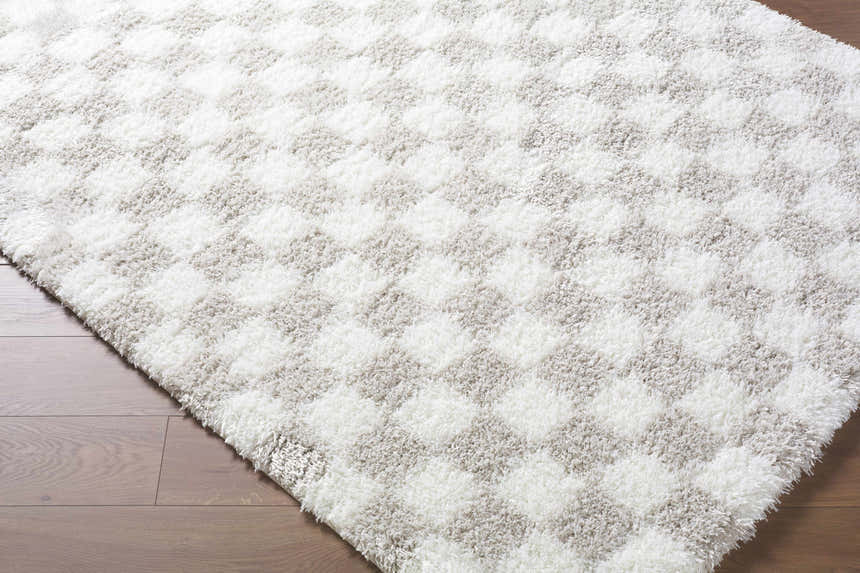 Close up of the Ardice Area Rug, an ivory and peach shag rug with a geometric checkerboard pattern. Corner